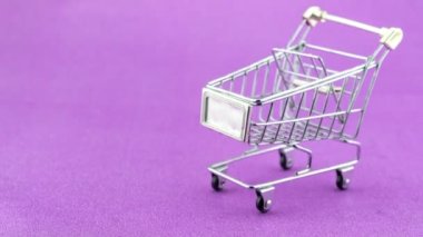 Dur hareketli animasyon alışveriş arabası mor kağıt arka planda madeni para ile. Stop motion Thai banyo madeni para alışveriş konsepti işi için el arabasında.