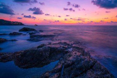 Dramatik gökyüzünün günbatımı manzaralı kayalıklı uzun pozlama görüntüsü..