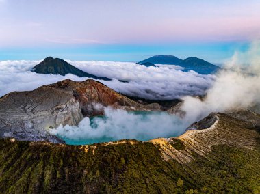 Kawah Ijen volkanındaki kayalıkların gündoğumunda turkuaz sülfür gölü manzarası. Doğu Java, Endonezya 'da büyüleyici doğa manzarası. Doğal manzara rengarenk gökyüzü arka planı.