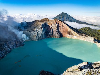 Kawah Ijen volkanındaki kayalıkların gündoğumunda turkuaz sülfür gölü manzarası. Doğu Java, Endonezya 'da büyüleyici doğa manzarası. Doğal manzara rengarenk gökyüzü arka planı.