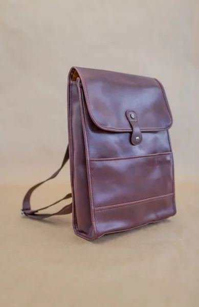 Brown leather backpacks isolated on beige background. Unisex bag