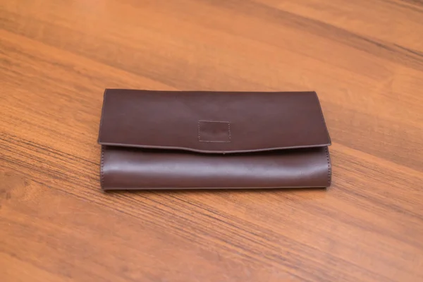 Brown leather wallet on the wooden table. Unisex wallet.