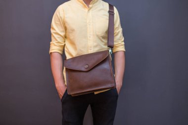 Elinde kahverengi deri bir çanta olan bir adam. Satılık üniforma çantası.