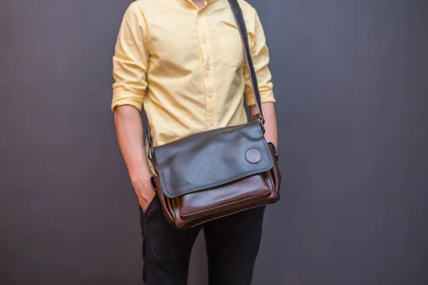 Brown leather messenger bag in the hand on a man. Unisex bag for sale.