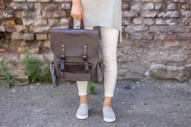 Elinde gri bir sırt çantası olan bir kadın. Satılık üniforma çantası.