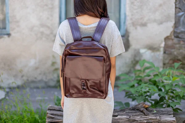 Back of woman with brown leather backpack. Unisex bag for sale. Unbranded backpack.