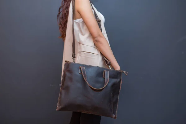 Woman holding brown leather backpacks in the hand. Unisex bag