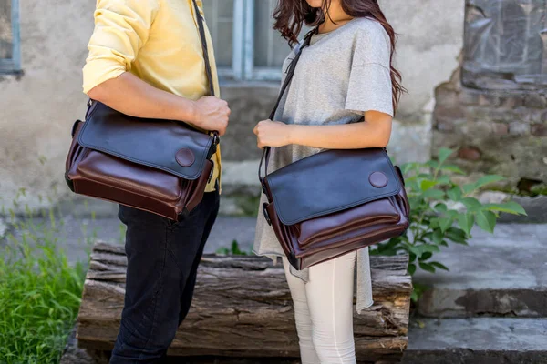 Man and woman with brown leather messenger bag in the hand. Unisex bag