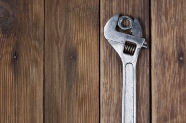 Ahşap arka planda İngiliz anahtarı ve vida fındığı