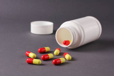 Gri arka planda haplar ve vitaminler için beyaz kavanoz