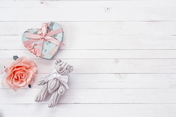 Un osito de peluche pequeño, corazón y rosa sobre un pla de madera pintado de blanco —  Fotos de Stock