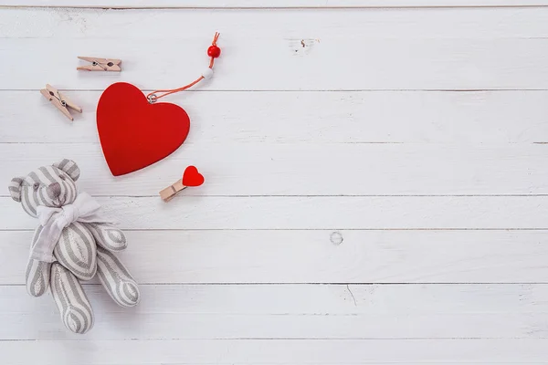 Un piccolo orsacchiotto, cuori e mollette su un due bianco dipinto — Foto Stock