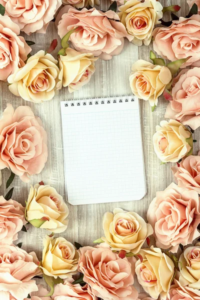 Background with rose flowers and empty notebook for text on wood — Stock Photo, Image