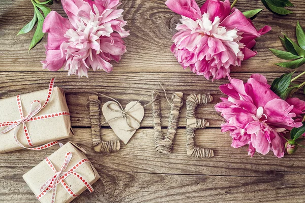 Peonías moradas con letras LOVE y cajas de regalo en viejo bo de madera — Foto de Stock