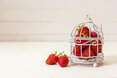 Beyaz bir arka plan dekoratif bir kafeste olgun çilek. 