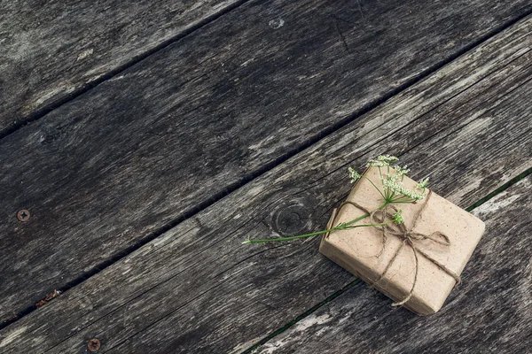 Fondo con caja de regalo y flor en tablas grunge de madera . — Foto de Stock