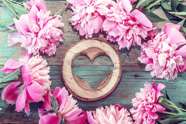 Roze pioenrozen en hart gesneden in hout op de oude grunge geschilderd — Stockfoto