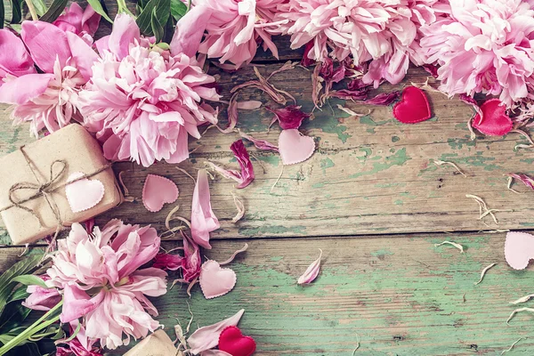 Achtergrond met roze pioenrozen, doos van de gift en harten op oude groene b — Stockfoto