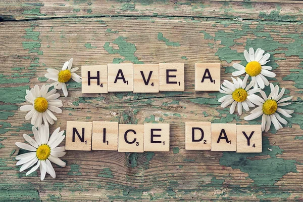 Wish a good day with daisies on an old wooden background. Letter