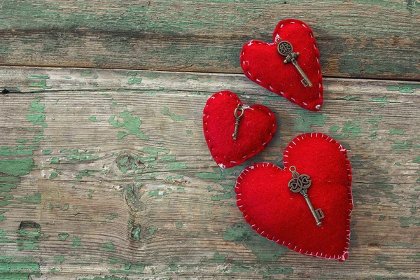 Rote Herzen mit antiken Schlüsseln auf alten bemalten Holzbrettern. — Stockfoto