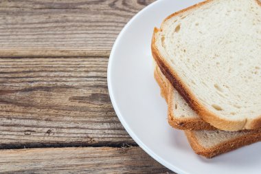Beyaz ekmek dilimleri ahşap bir masa üzerinde bir plaka üzerinde bir yığın.