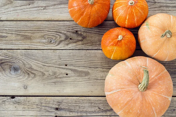 Background with a few pumpkins on the old wooden boards. Space f — Stock Photo, Image