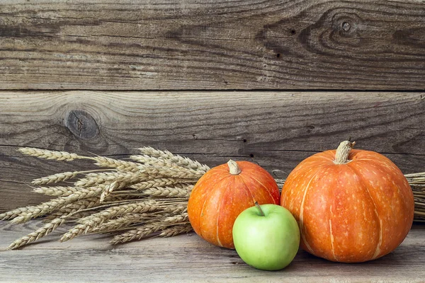 Stilleven met oranje pompoen, groene appel en oren van tarwe op — Stockfoto