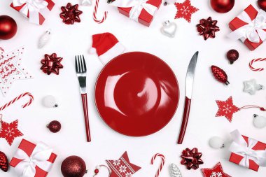 Kırmızı ve beyaz Noel sofrası çatal bıçak takımı, hediyeler ve kırmızı masa süsleriyle. Üst görünüm. 