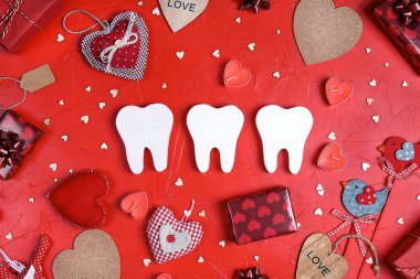 Kırmızı arka planda hediyeler ve kalplerle çevrili beyaz dişler. Diş hekimi Sevgililer Günü kartı. Sevgililer Günü konsepti. 