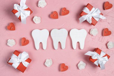 Pembe arka planda hediyeler, kalpler ve güllerle çevrili beyaz dişler. Diş hekimi Sevgililer Günü kartı. Sevgililer Günü konsepti.  