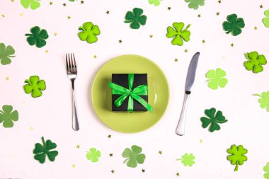 St. Patrick günü için sofra takımı, dekoratif yonca yaprakları, hediyeler ve beyaz masada altın yıldızlarla. Üst görünüm.