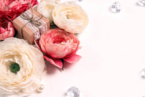 Festive romantic white background with peony flowers, gift and crystals. Top down composition with copy space. Valentine's Day, Mother's Day or 8 March greeting card.