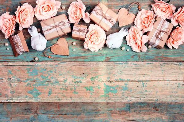 Festive background with rose flowers, gifts and birds on shabby wooden turquoise boards. Border top down composition with copy space. Valentine\'s Day, Mother\'s Day or 8 March greeting card.