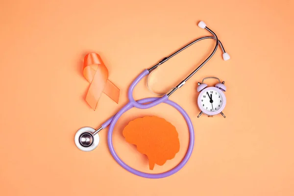World Multiple Sclerosis Day. Orange awareness ribbon, brain symbol, stethoscope and alarm clock on a orange background.