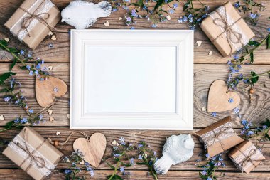 Boş beyaz çerçeve, çiçekler, hediyeler, kuşlar ve kalpler eski tahta tahtalarda. Metin için kopyalama alanı olan üst görünüm.