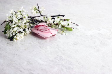 Açık mermer arka planda elma çiçeği dallı pembe kağıt origami tankı. Metin için alanı kopyala.