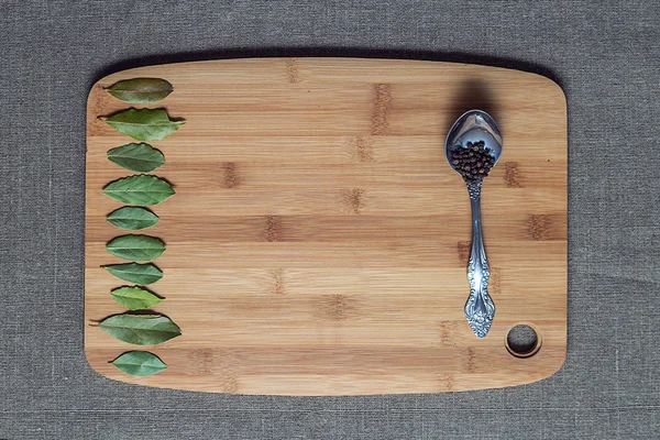 Bay leaves and black pepper in a spoon on the board — Stock Photo, Image