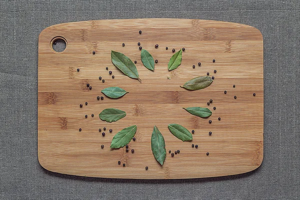 Bay leaves and black pepper on a wooden board — Stock Photo, Image