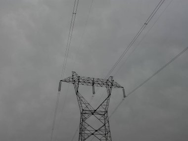 Şehirdeki elektrik hatları. Elektrik kabloları mavi gökyüzünün altındaki bir sokak elektrik direğine bağlı..