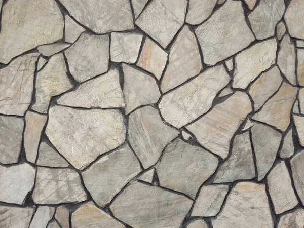 Background of stone wall texture. Seamless masonry wall with irregular shaped stones. Granite pavement.
