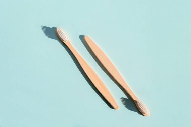 Açık mavi arka planda iki çevre dostu bambu ahşap diş fırçası. Sert ışık. Yukarıdan görüntüle