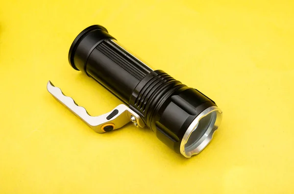 Black Flashlight on yellow table banner top view — Stock Photo, Image