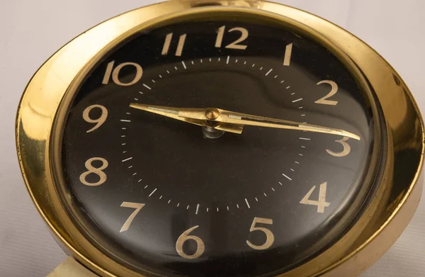 Gold color table clock showing 9 o clock time closeup.