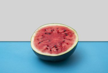 Mavi masa arkaplanındaki yarısı kesilmiş karpuz yaz konseptini gösteriyor..