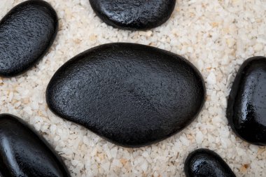 Beyaz çakıl arkaplanda siyah masaj taşları.
