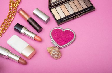 Pembe pankartta farklı makyaj ve cilt ürünleri.