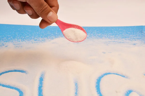 Cuchara llena de azúcar con fondo dulce — Foto de Stock