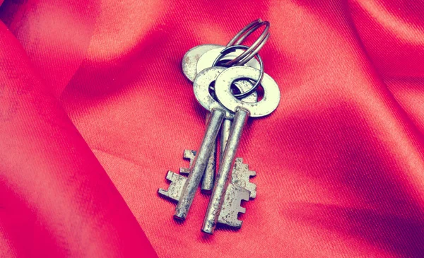 Kunci vintage lama pada kain merah — Stok Foto
