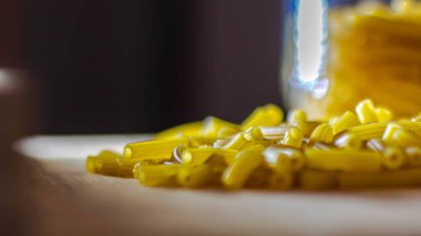 Mutfaktaki masada çiğ makarna var.