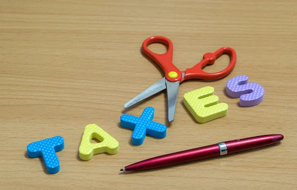Tesoura e o alfabeto plástico TAXES . — Fotografia de Stock